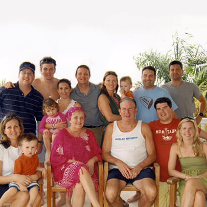 A large family poses for a photo in a tropical outdoor setting.