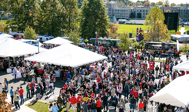 A vibrant outdoor event filled with a large crowd of people, engaged in various activities and enjoying the lively environment.