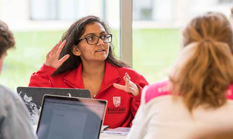 a girl in red jacket raises hand in class.