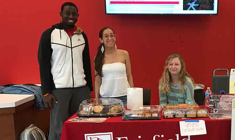 three students behind red table at activities fair