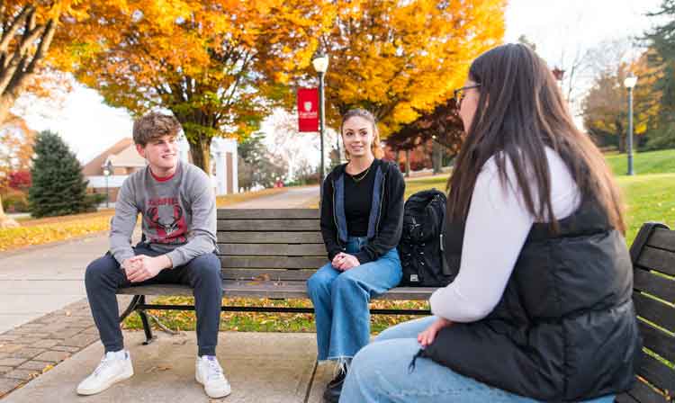 A group of people sits on benches outdoors.