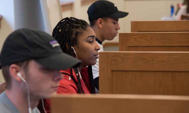 Students sit in library cubbies.