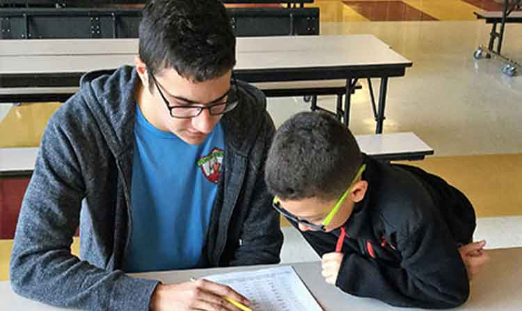 student helping a child with classwork at a table