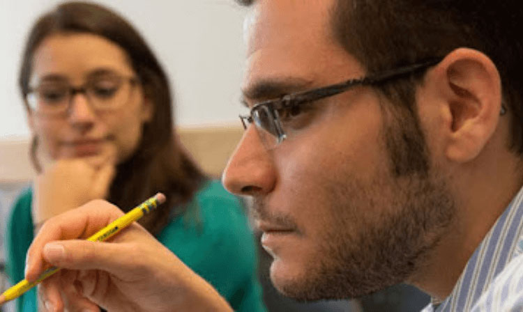 A student holds a pencil in his hand. 