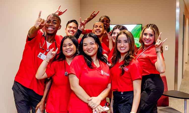 A group of individuals wearing red shirts smiles and poses together for a photograph.