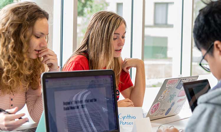 Nursing students working at a table in Egan on their laptops 