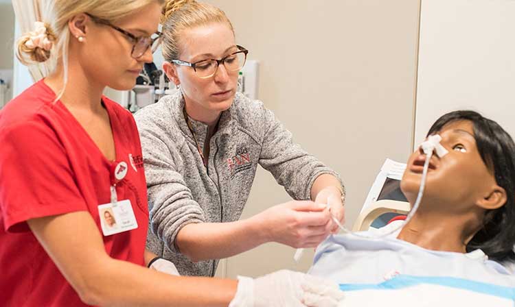 Two nursing students work together on a manikin.