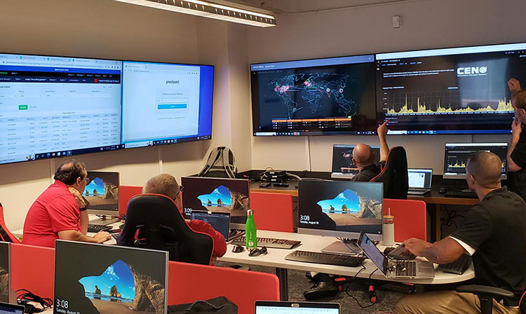 Students sit in a computer lab full of desktops and screens as they look at tech map on main screen.