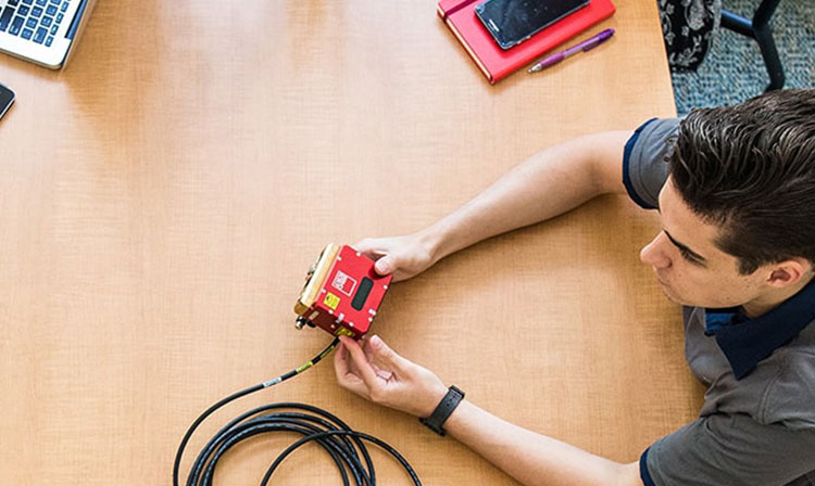 A man focused on his work, using a red device.