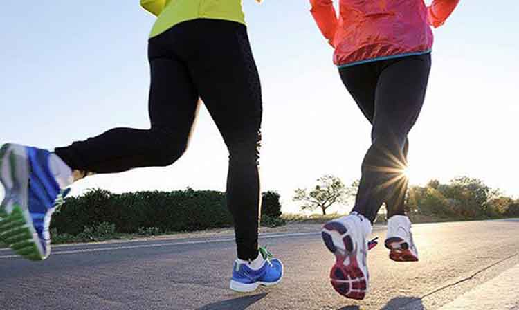 A low angle of two people running in leggings and sneakers.