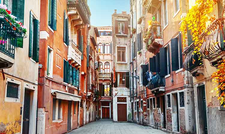 A cobblestone street with tall buildings on each sides.