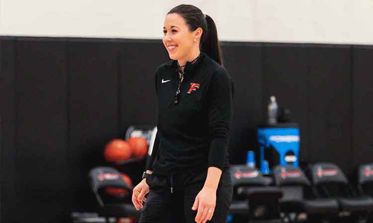 Coach Carly smiles on the sideline at her basketball camp