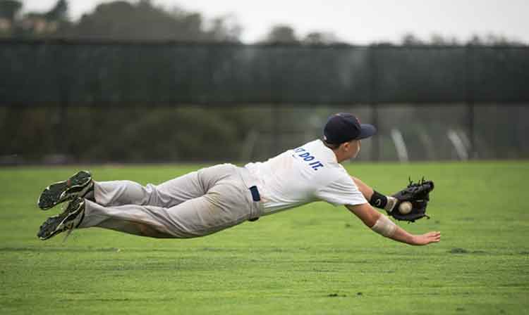 Baseball player makes a diving catch in the outfield 