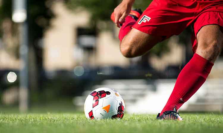 Lower body shot of soccer player right before they kick the ball 