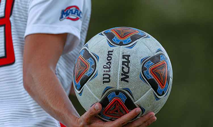 Soccer player holding soccer ball in left hand, close up shot 