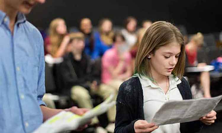 Young student reads from paper in front of class 