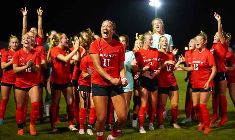 The women's soccer team joyfully celebrates their national championship victory with smiles and team spirit.