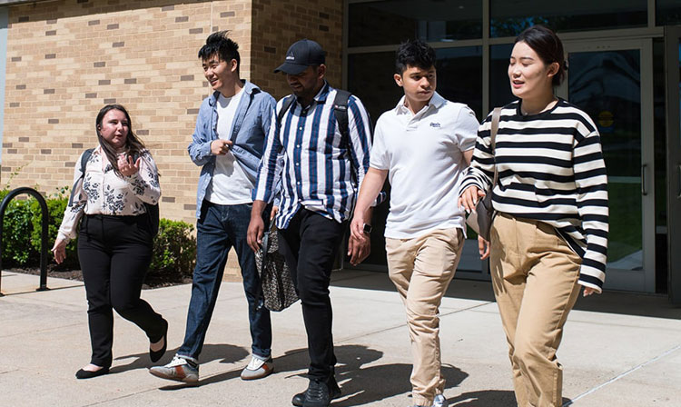 Five students walking out of a building on campus. 