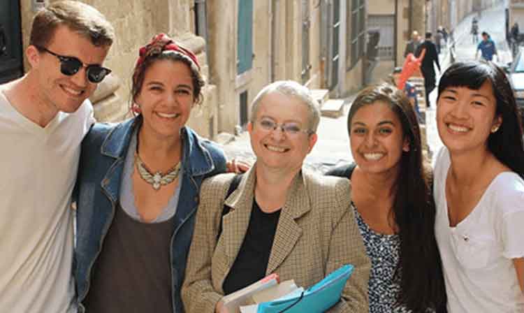 A group of students stand with a professor on a street.