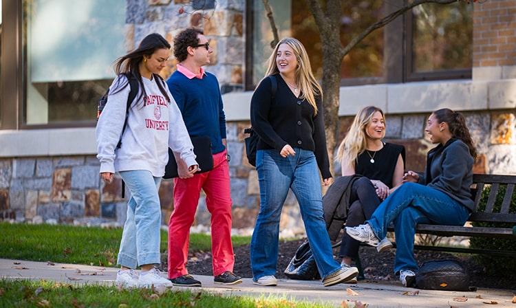 Students talking and laughing as they cross campus to go to class together.