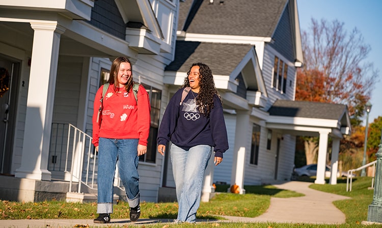 Two female students walking to class from the Barnyard Manor townhouses.