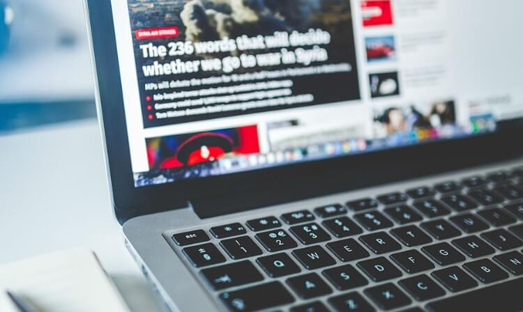 A laptop screen shows an article titled “The 236 words that will decide whether we go to war in Syria”. 