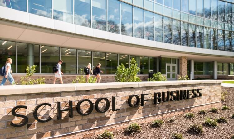 Exterior shot of the dolan school of business sign in front of building.