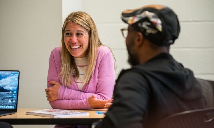 Two students laugh in a classroom.