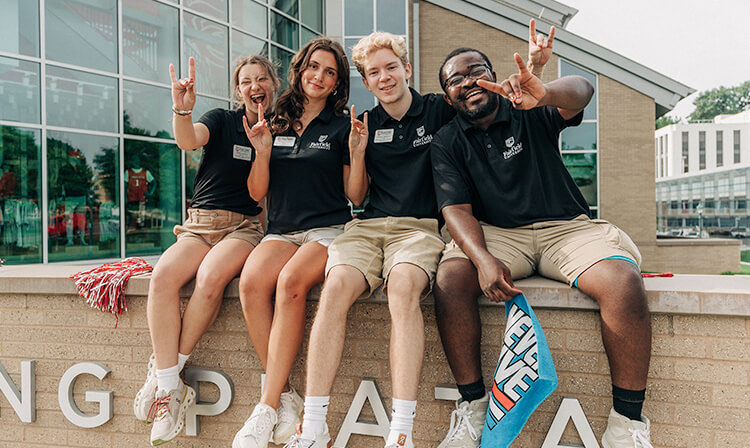 Students sitting together throwing up the stag hand sign. 