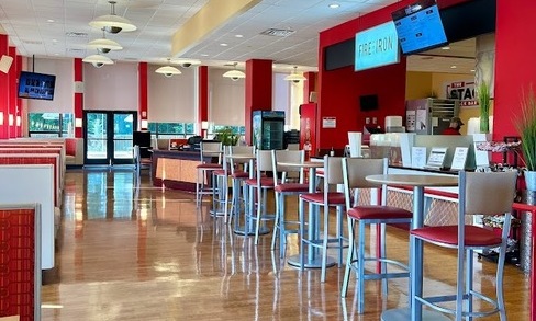 Rows of tables and chairs are next to booths.