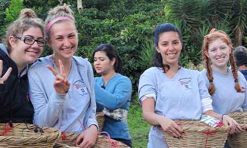 our people smiling and holding baskets outdoors, with greenery in the background.