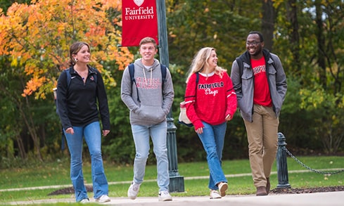 A group of students in Fairfield merch walks outdoors smiling.