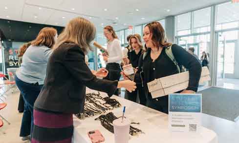 Staff welcome and check in students at a reception desk 