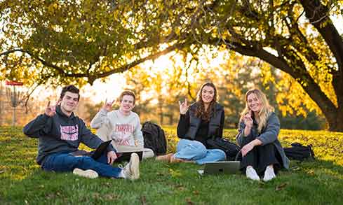 four students sitting in grass.