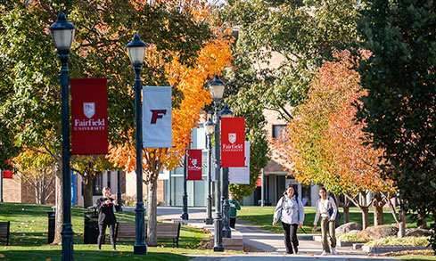 A scenic walkway lined with trees, featuring people strolling along the path.