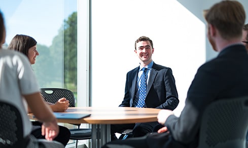 Students wearing formal attire sitting around a table. 