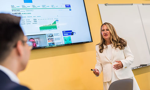 A professor giving a lecture about stocks with one student in the frame out of focus.