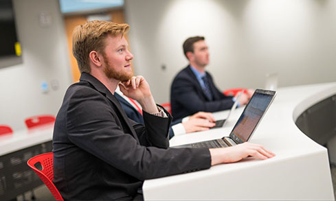 Students wearing formal attire listening to a lecture.