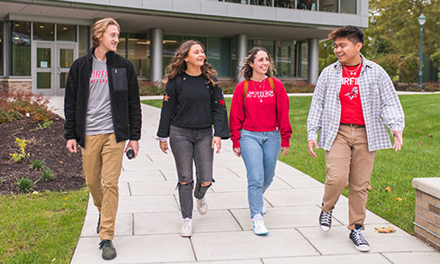 Four students walking out of the business school. 