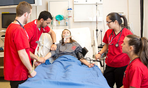 A team of nurses caring for a patient in a hospital room, focused and working together to provide support.