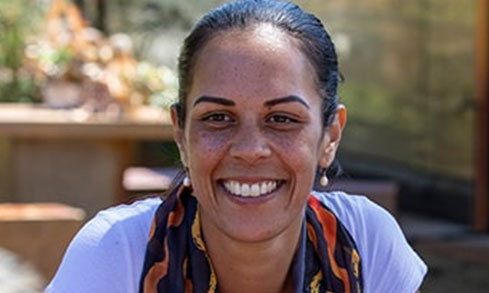 Student smiles at camera with outdoor background.