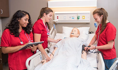 3 nursing students work together on a manikin.