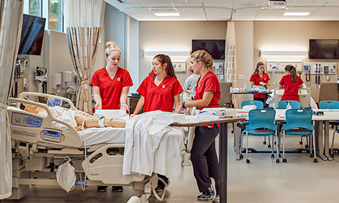 Wide angle shot of multiple groups of nursing students working in multiple pods.