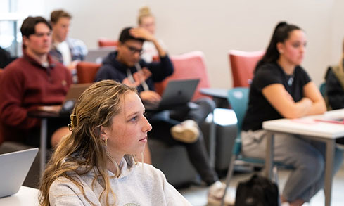 Group of nursing students listen to a lecture with laptops.