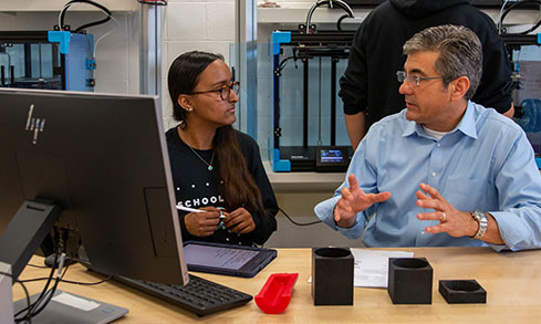 Professor sits with student one-on-one and explains something to her. 