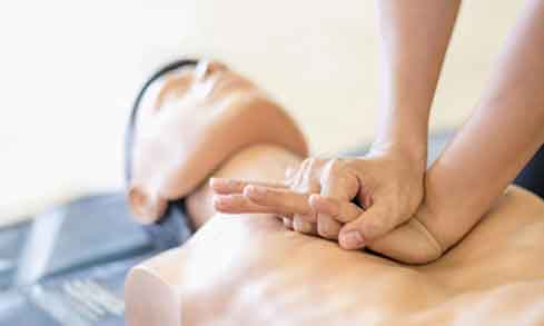 A person delivers CPR to a manikin.