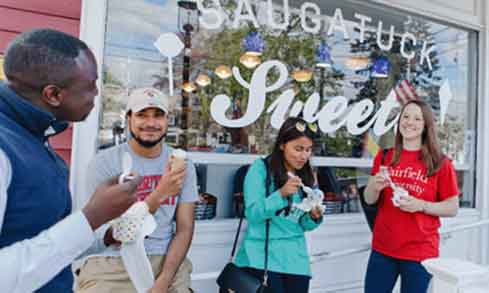 Students eating ice cream together and standing in front of Saugatuck Sweets in downtown Fairfield. 