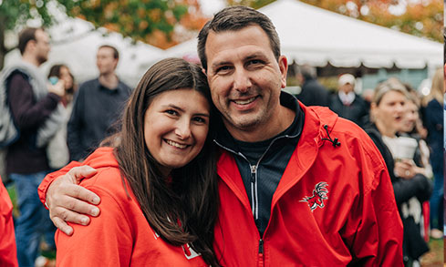 A man and woman in red jackets smiling together for a photo.