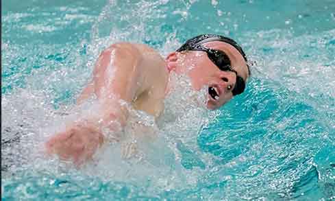 A person in black goggles swims in a pool. 