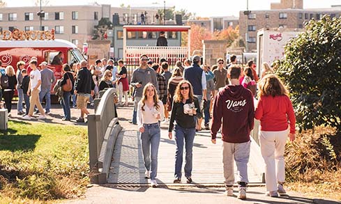 Image of several people outside by food trucks